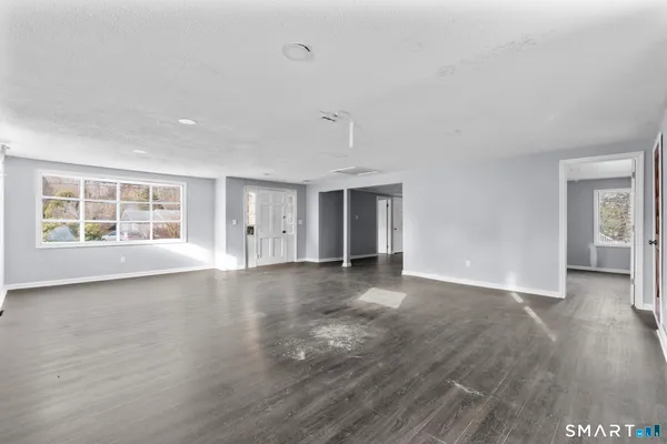 a view of an empty room with wooden floor and a window
