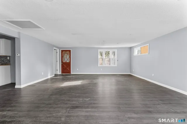 a view of an empty room with wooden floor and a window