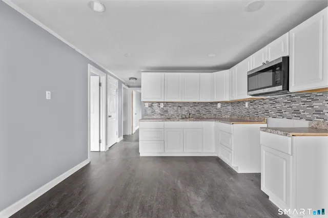 a kitchen with granite countertop white cabinets and stainless steel appliances