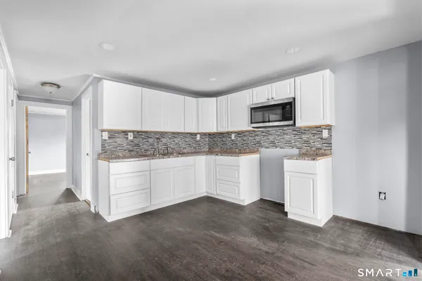 an empty room with wooden floor cabinet and windows