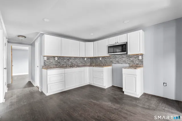 an empty room with wooden floor cabinet and windows