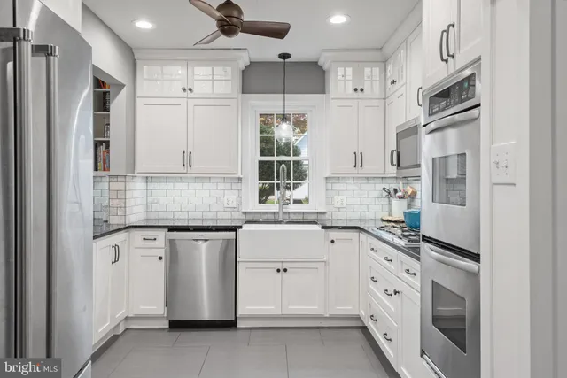a kitchen with granite countertop a white refrigerator oven a sink dishwasher and white cabinets next to a window
