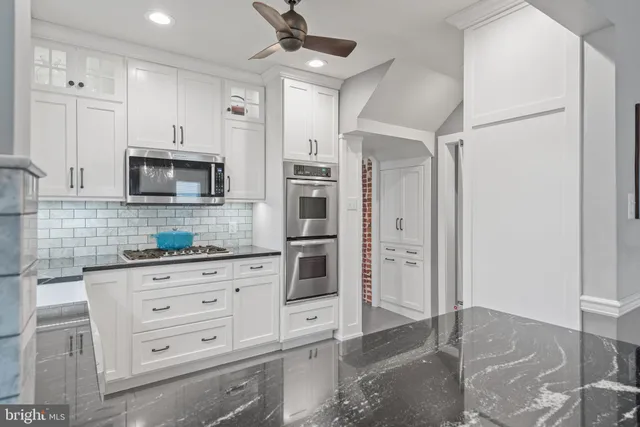 a kitchen with white cabinets and stainless steel appliances