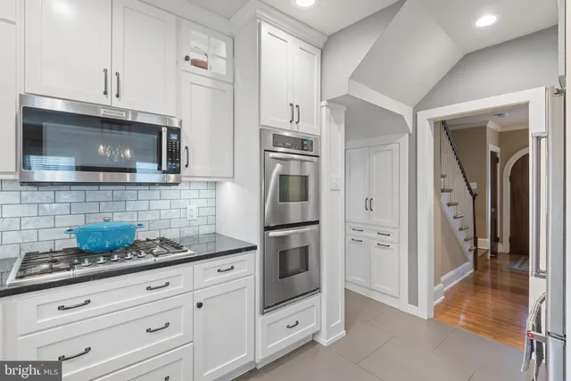 a kitchen with granite countertop white cabinets stainless steel appliances and a counter space
