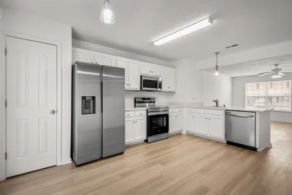 a kitchen with granite countertop white cabinets stainless steel appliances a sink and dishwasher