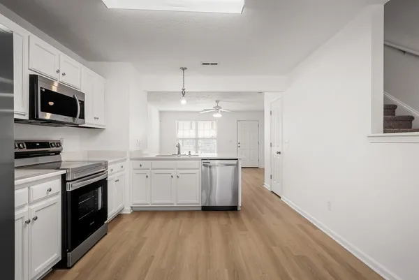 a large kitchen with a wooden floor and white stainless steel appliances
