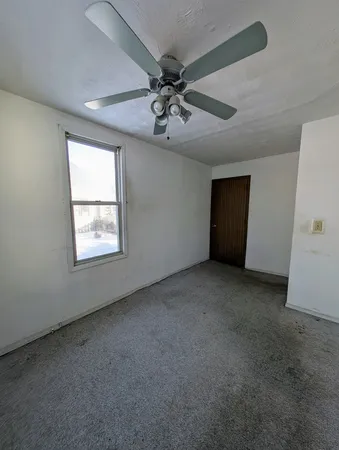 an empty room with a ceiling fan and window