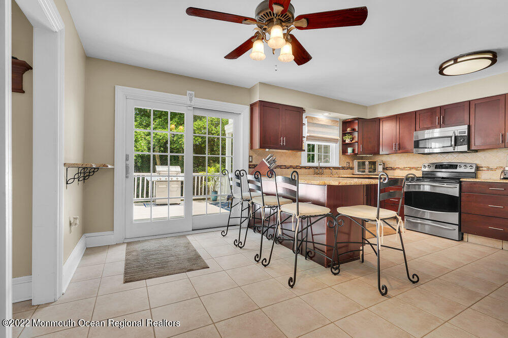 1722 Burrsville Road Brick, NJ 08724 - Photo 32 of 71 a open kitchen with stainless steel appliances granite countertop a stove top oven a sink a dining table and chairs with the bookshelf