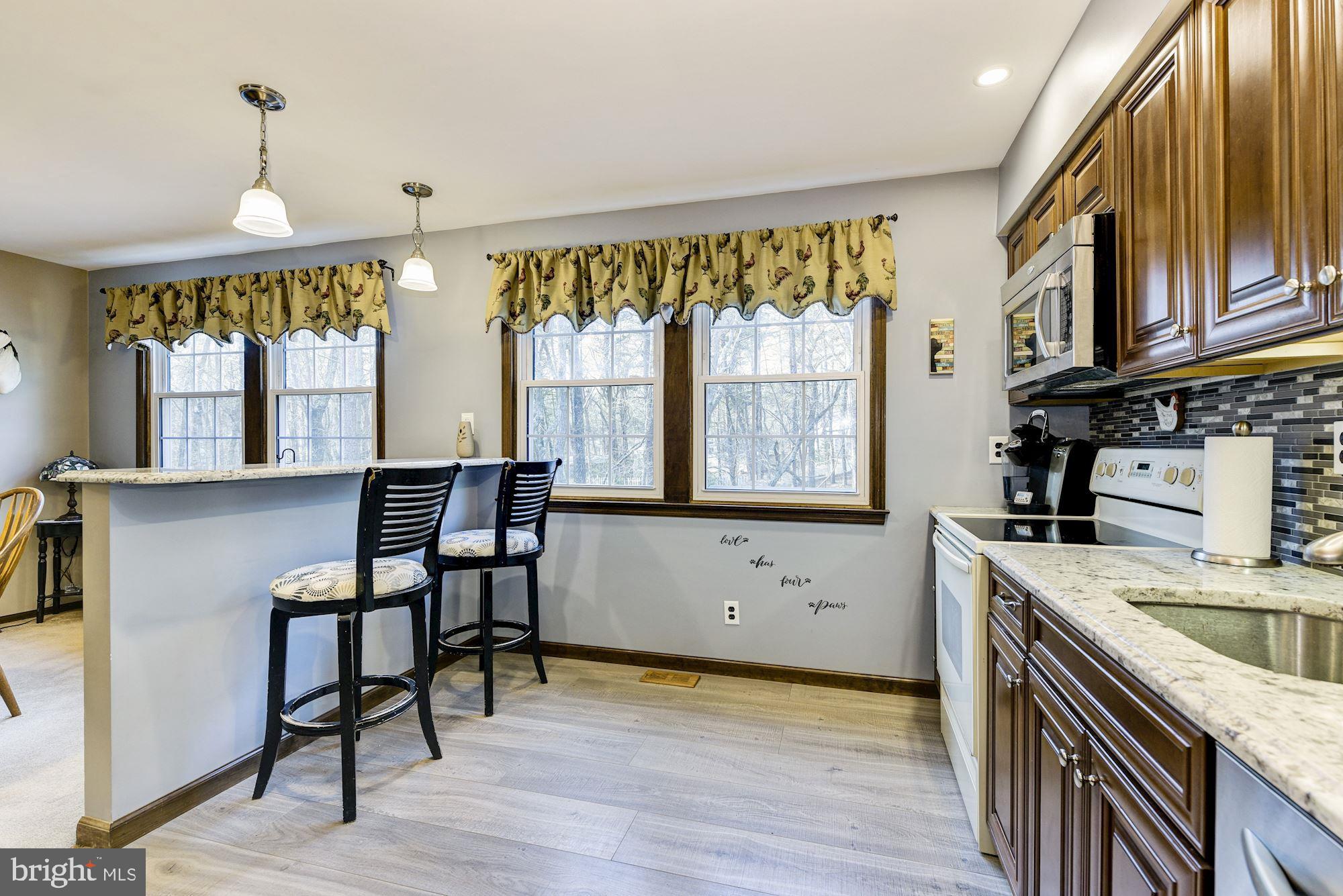 5 Spring Drive Tabernacle, NJ 08088 - Photo 10 of 29 a kitchen with granite countertop a stove a sink a dining table and chairs with wooden floor