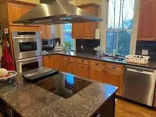 a kitchen with stainless steel appliances granite countertop a sink a stove and a wooden cabinets