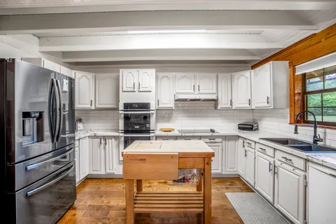 a kitchen with stainless steel appliances granite countertop a sink a stove a refrigerator and cabinets