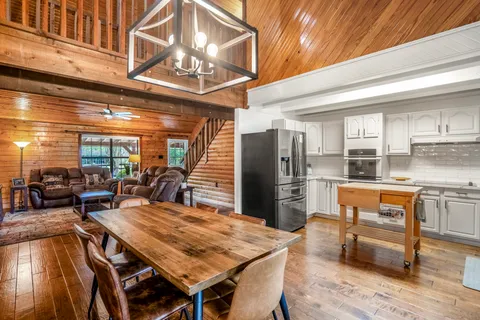 a dining hall with stainless steel appliances kitchen island granite countertop a table chairs and a refrigerator