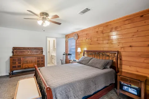 a bedroom with a bed and dresser with wooden floor