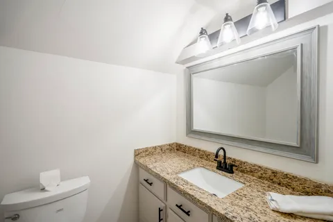 a bathroom with a granite countertop sink a toilet and a mirror