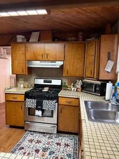 a kitchen with stainless steel appliances granite countertop a stove a sink and a microwave