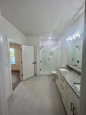 a bathroom with a granite countertop sink a toilet a large mirror and vanity