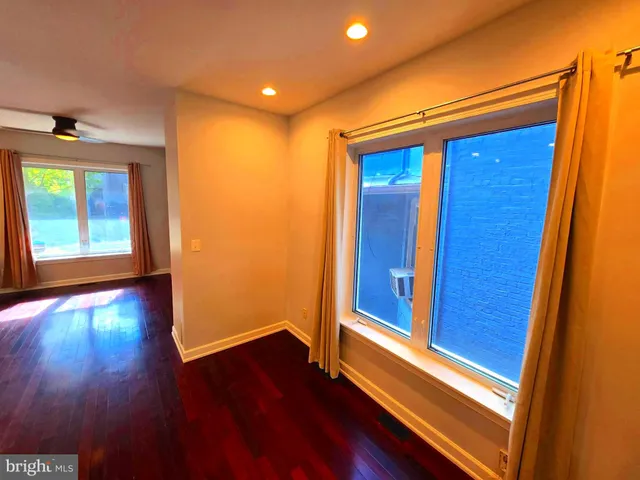 a view of an empty room with a window and wooden floor
