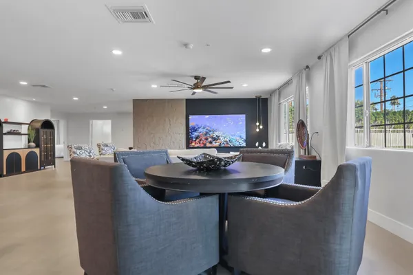 a dining room with furniture a floor to ceiling window and kitchen view