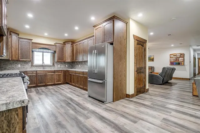 a kitchen with stainless steel appliances granite countertop a refrigerator oven stove a sink dishwasher and a oven with wooden floor