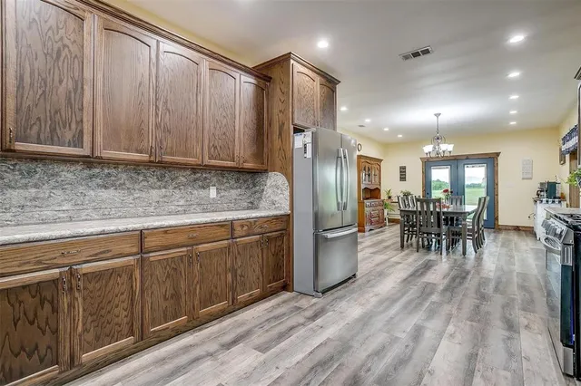 a kitchen with stainless steel appliances granite countertop a refrigerator dining table and chairs