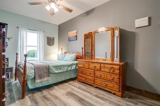 a bedroom with a bed and dresser with wooden floor