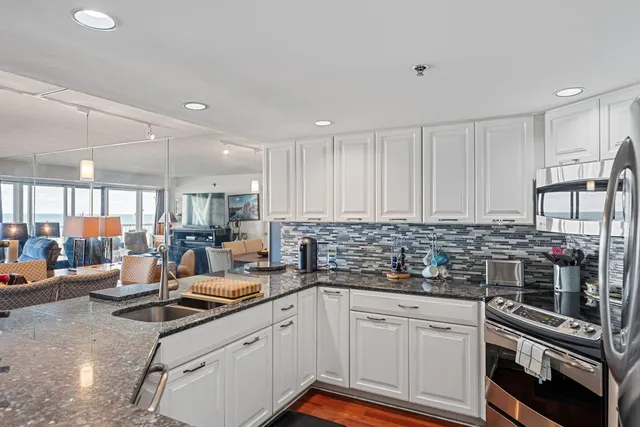 a kitchen with stainless steel appliances a stove a sink and white cabinets
