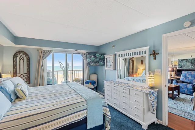 a bedroom with a balcony a bed and dresser with mirror