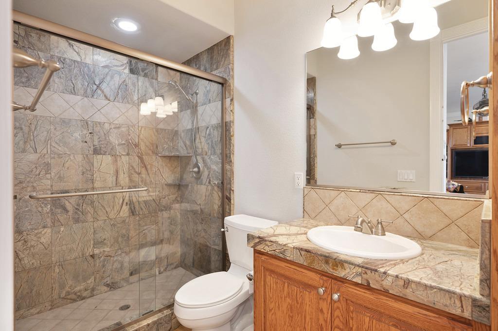 5901 Traverse Creek Road Garden Valley, CA 95633 - Photo 38 of 98 a bathroom with a granite countertop sink a mirror and a toilet