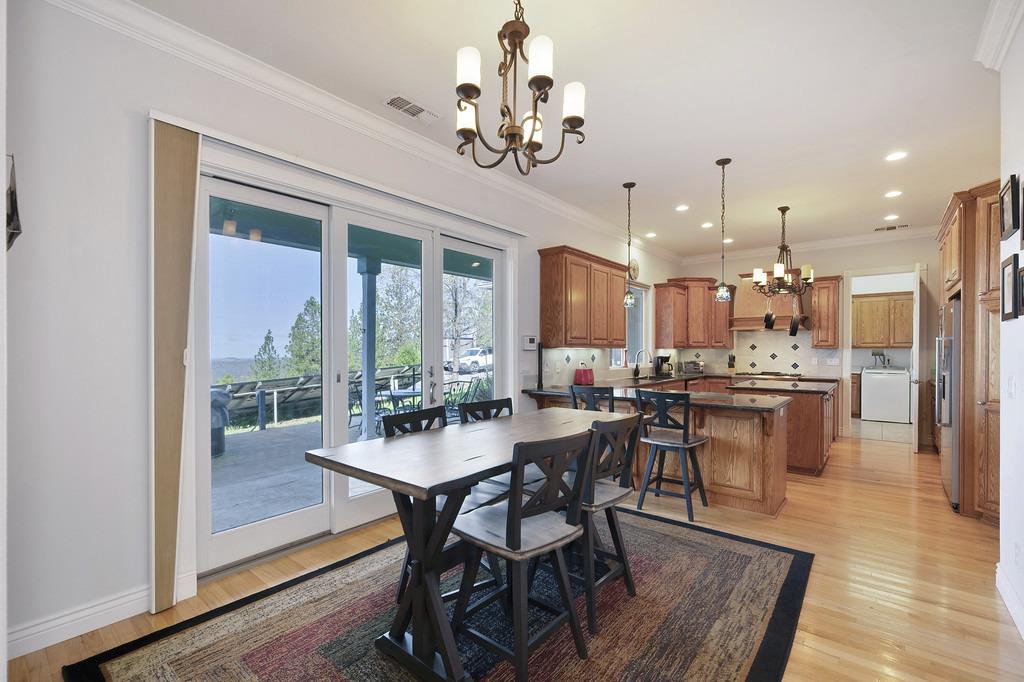 5901 Traverse Creek Road Garden Valley, CA 95633 - Photo 39 of 98 a dining room with wooden floor a chandelier a wooden table and chairs