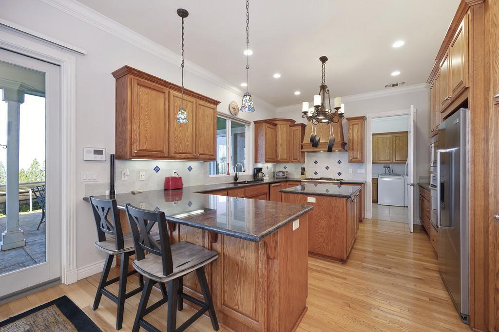 5901 Traverse Creek Road Garden Valley, CA 95633 - Photo 43 of 98 a kitchen with granite countertop a table chairs a sink dishwasher refrigerator and cabinets