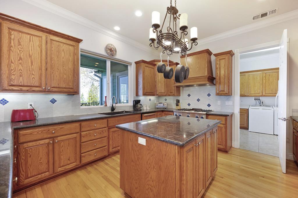 5901 Traverse Creek Road Garden Valley, CA 95633 - Photo 44 of 98 kitchen with wood finish cabinets, dark stone counters, a center island, washer / clothes dryer, and ornamental molding
