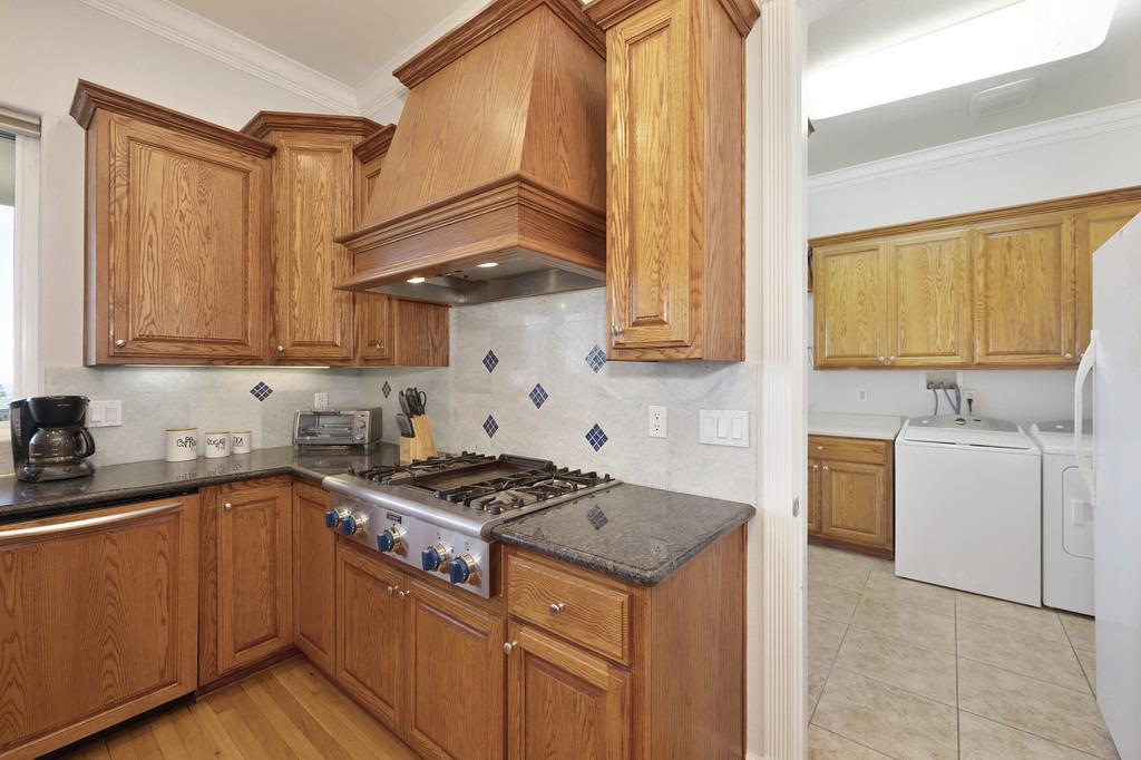 5901 Traverse Creek Road Garden Valley, CA 95633 - Photo 48 of 98 kitchen with wood finish cabinetry, ornamental molding, stainless steel gas stovetop, dark stone counters, and backsplash