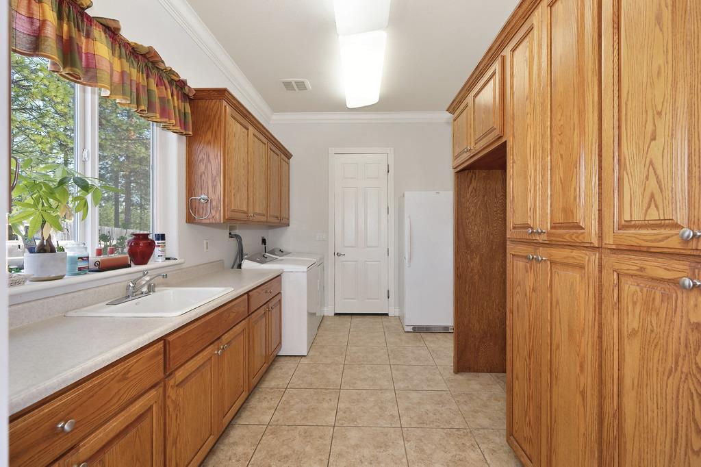 5901 Traverse Creek Road Garden Valley, CA 95633 - Photo 51 of 98 laundry area featuring cabinet space, crown molding, washer and dryer, and light tile patterned flooring