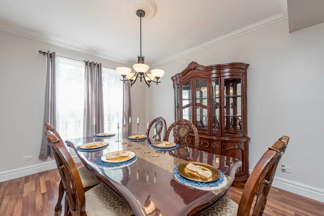 a dining room with wooden floor a chandelier a wooden table and chairs