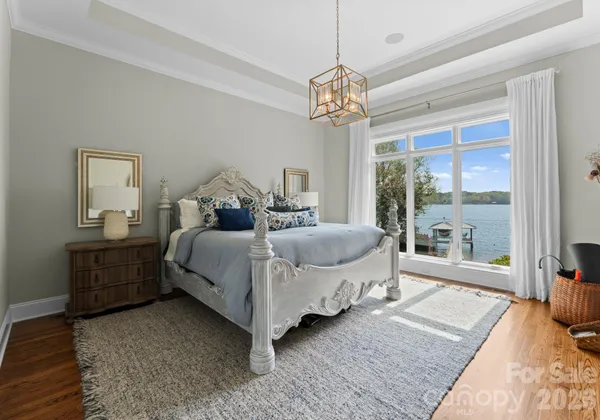 a spacious bedroom with a bed a chandelier and a large window