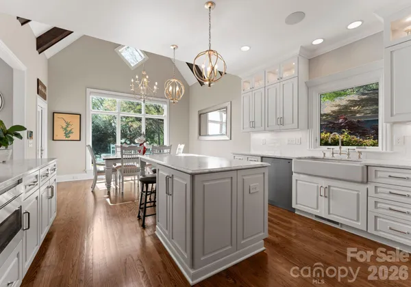 a kitchen with granite countertop a stove a sink a dining table and chairs