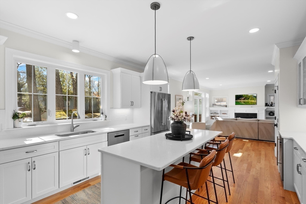 96 Winchester Road Arlington, MA 02474 - Photo 5 of 34 a kitchen with stainless steel appliances kitchen island granite countertop a stove a sink a dining table and chairs with wooden floor