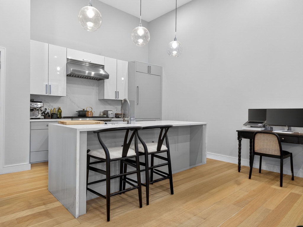 355 Congress Street, Unit 501 Boston, MA 02210 - Photo 5 of 16 a kitchen with a dining table chairs and white cabinets