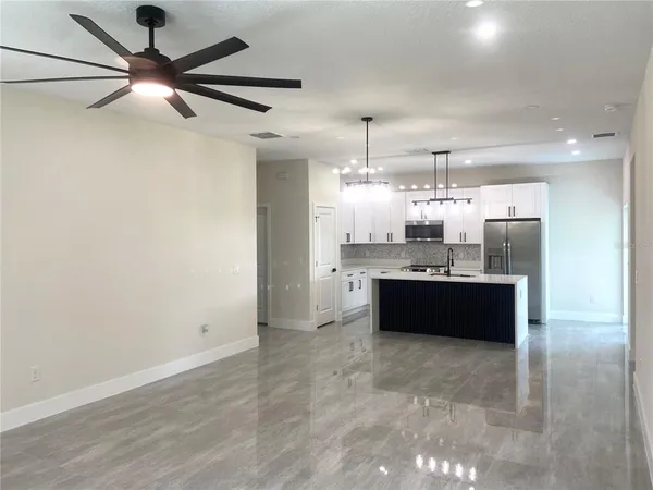 a large room with a kitchen and a chandelier fan