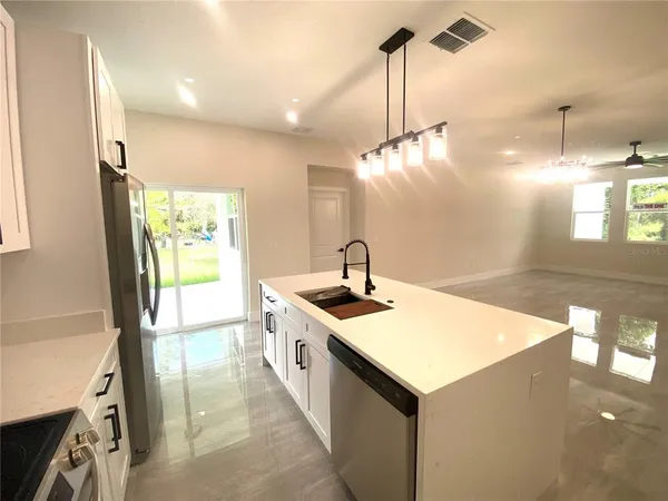 a kitchen with a stove a sink a refrigerator and windows