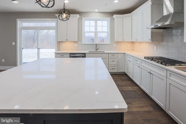 a large kitchen with stainless steel appliances kitchen island a large counter top and a wooden floors