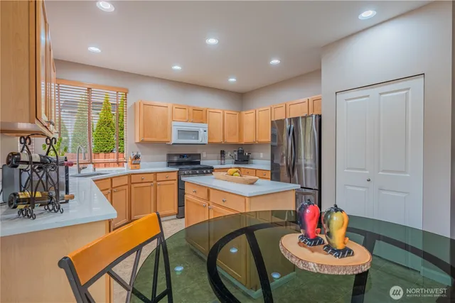 a kitchen with stainless steel appliances granite countertop a refrigerator a stove a sink dishwasher with a dining table and chairs