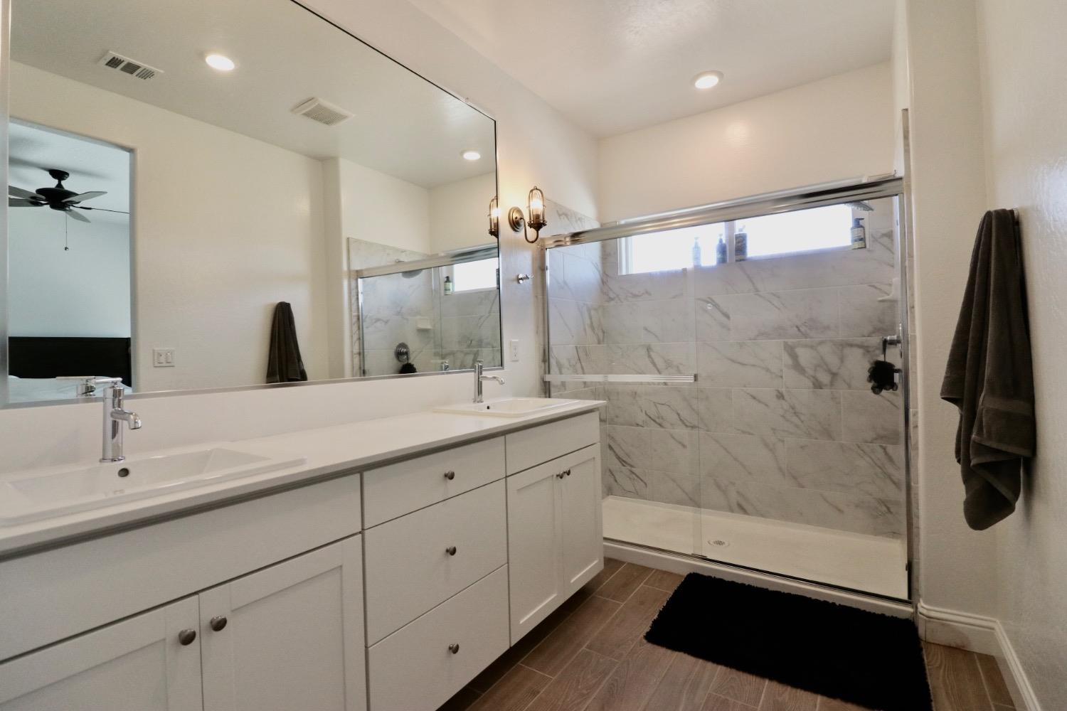 240 Huntington Avenue Madera, CA 93636 - Photo 15 of 24 a bathroom with a double vanity sink a toilet a mirror and shower