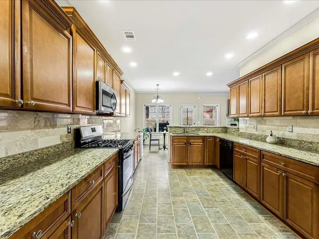 a large kitchen with stainless steel appliances granite countertop a large counter top a stove a sink a refrigerator and cabinets