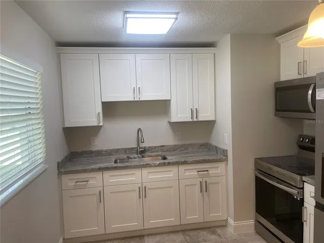 a kitchen with granite countertop white cabinets and stainless steel appliances