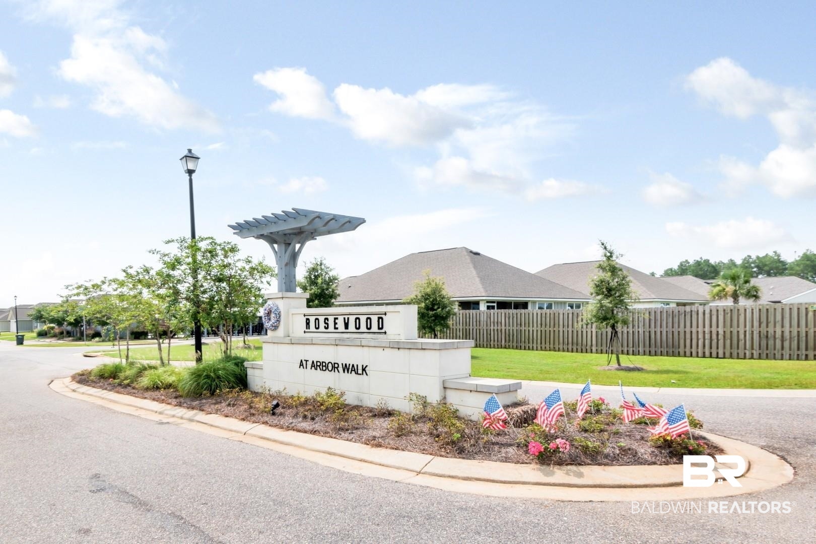1295 Hayward Loop Foley, AL 36535 - Photo 29 of 29 Community entrance featuring a stone monument with "Rosewood at Arbor Walk" lettering, a decorative pergola structure, and a street lamp