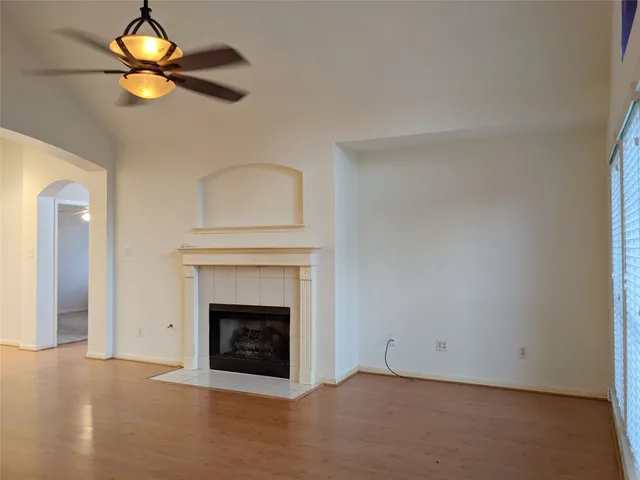 an empty room with a fireplace and a ceiling fan