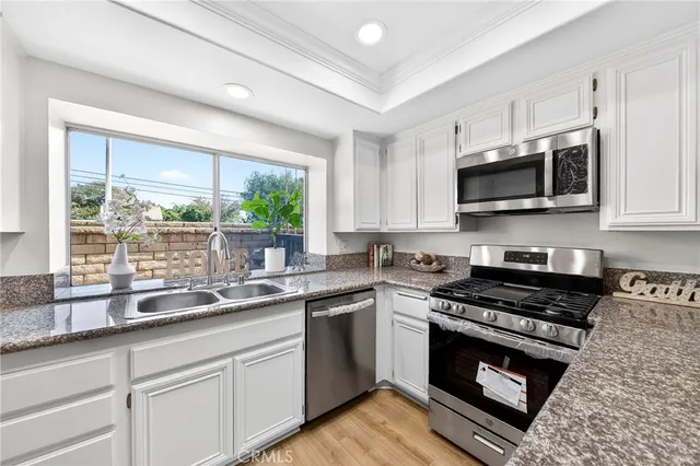a kitchen with granite countertop a sink cabinets stainless steel appliances and a window