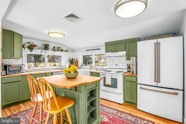 a kitchen with stainless steel appliances granite countertop a refrigerator a stove a sink and a dining table with wooden floor