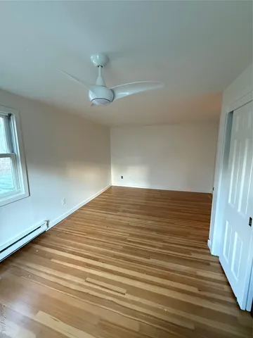 a view of empty room with wooden floor and fan